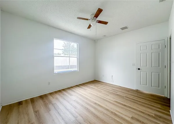 a view of empty room with wooden floor and fan