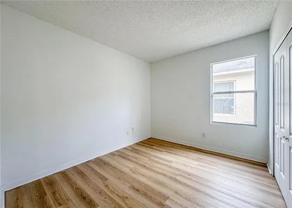 an empty room with wooden floor and ceiling fan
