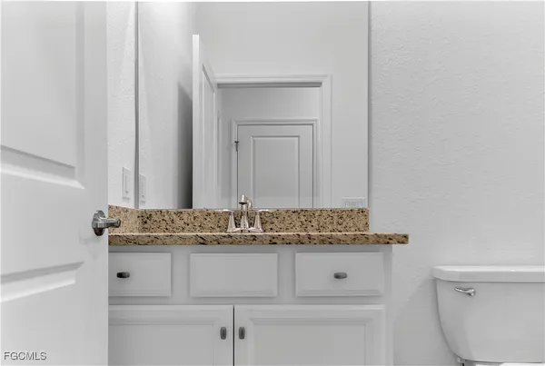 a bathroom with a granite countertop toilet sink and mirror