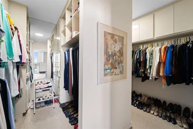 a view of walk in closet with clothes and shoes