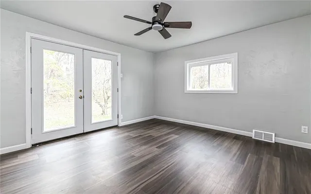an empty room with wooden floor and windows