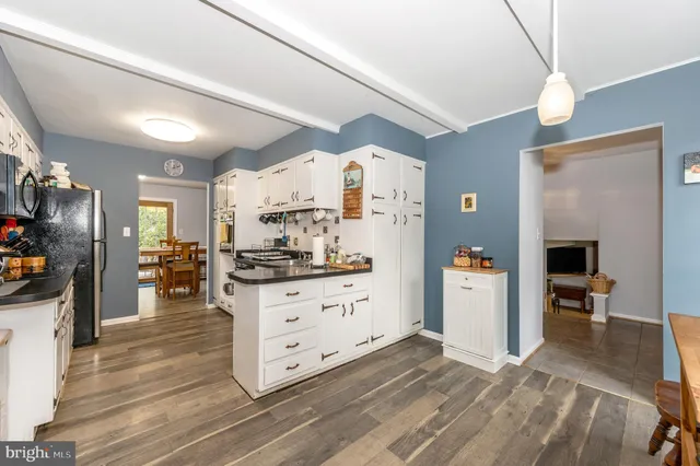 a kitchen with stainless steel appliances kitchen island granite countertop a refrigerator a stove and a sink with wooden floor