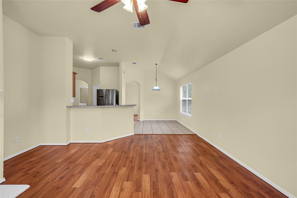 705 Loftin Street Crowley, TX 76036 - Photo 11 of 31 Unfurnished living room with ceiling fan, light wood-type flooring, lofted ceiling, and arched walkways