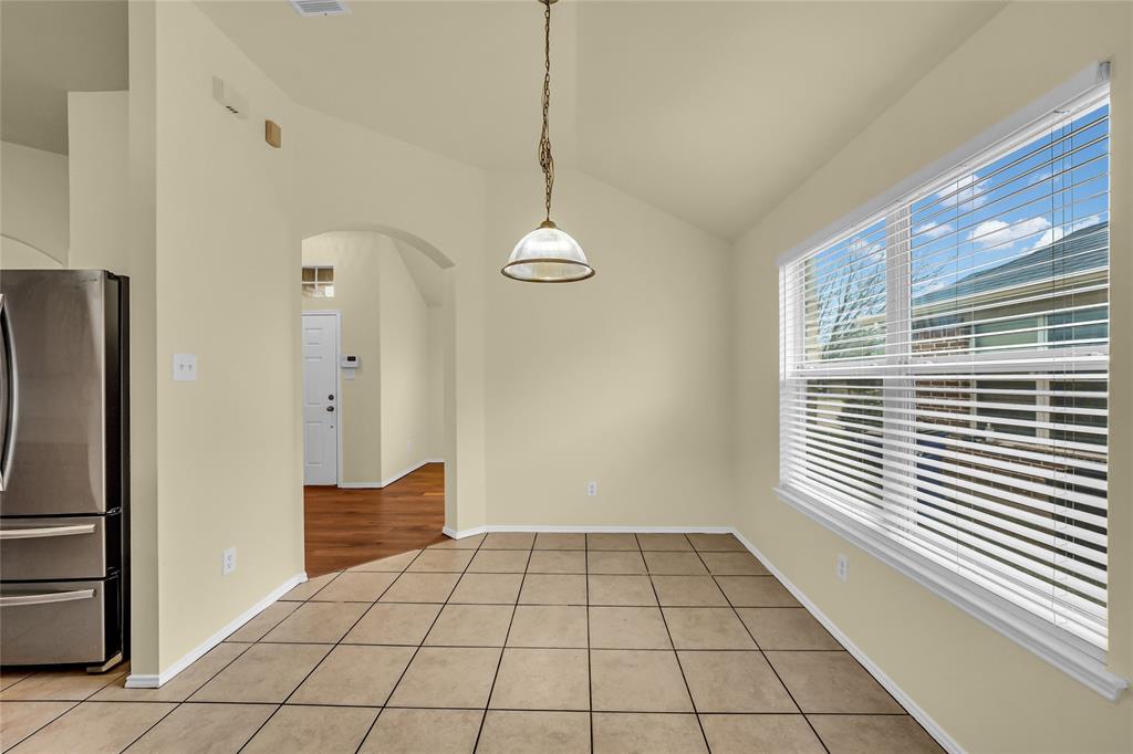 705 Loftin Street Crowley, TX 76036 - Photo 12 of 31 Unfurnished dining area featuring arched walkways, light tile patterned floors, and vaulted ceiling