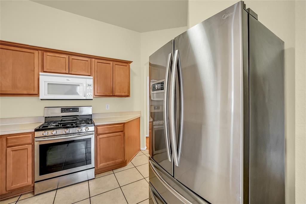 705 Loftin Street Crowley, TX 76036 - Photo 14 of 31 Kitchen with stainless steel appliances, light countertops, and wood finish cabinets