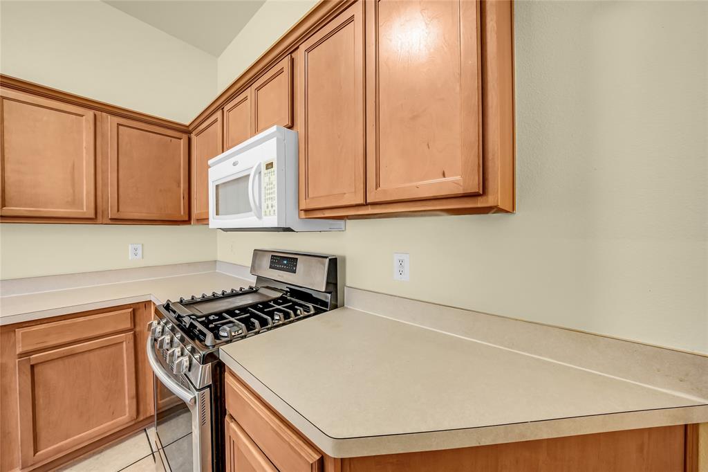 705 Loftin Street Crowley, TX 76036 - Photo 15 of 31 Kitchen with stainless steel gas stove, light countertops, wood finish cabinets, and light tile patterned floors