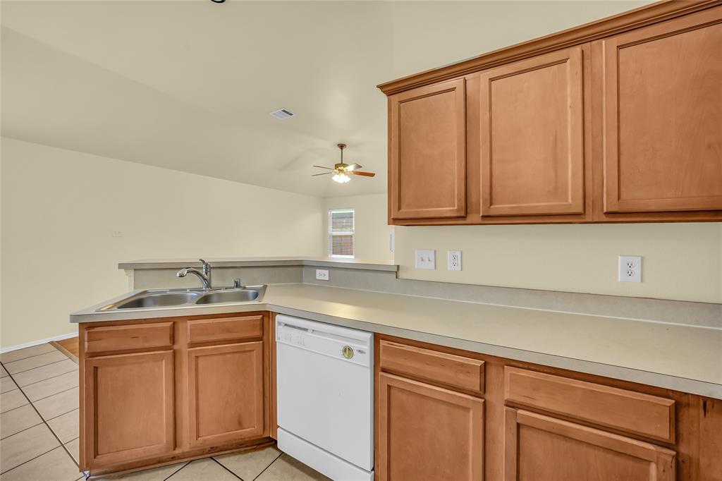 705 Loftin Street Crowley, TX 76036 - Photo 16 of 31 Kitchen with a peninsula, dishwasher, light tile patterned flooring, light countertops, and ceiling fan