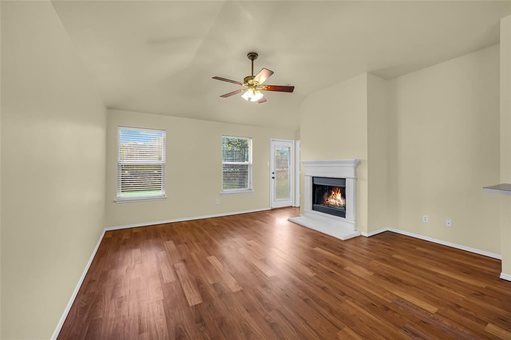705 Loftin Street Crowley, TX 76036 - Photo 8 of 31 Unfurnished living room with ceiling fan, dark wood-style floors, a glass covered fireplace, and lofted ceiling