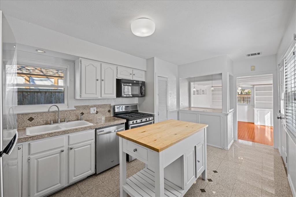 6043 Llano Avenue Dallas, TX 75206 - Photo 12 of 40 a view of a kitchen with a sink dishwasher stove and white cabinets with wooden floor