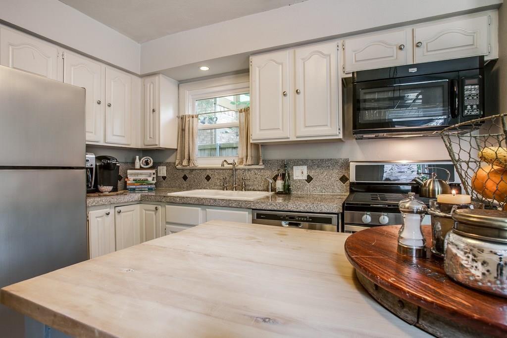 6043 Llano Avenue Dallas, TX 75206 - Photo 10 of 40 a kitchen with kitchen island granite countertop a stove top oven a sink dishwasher and white cabinets