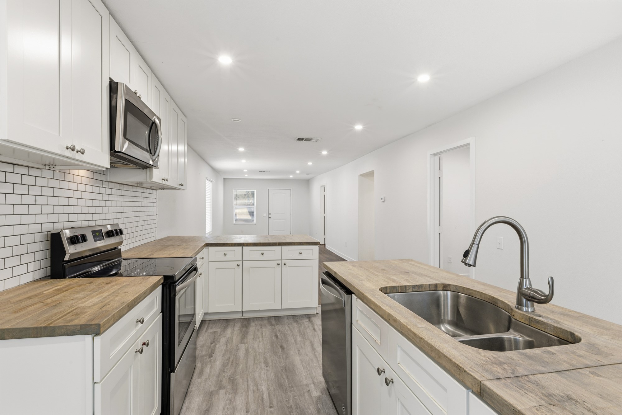 108 Irene Street Elgin, TX 78621 - Photo 11 of 29 Kitchen featuring stainless steel appliances, wood counters, white cabinetry, a peninsula, and recessed lighting