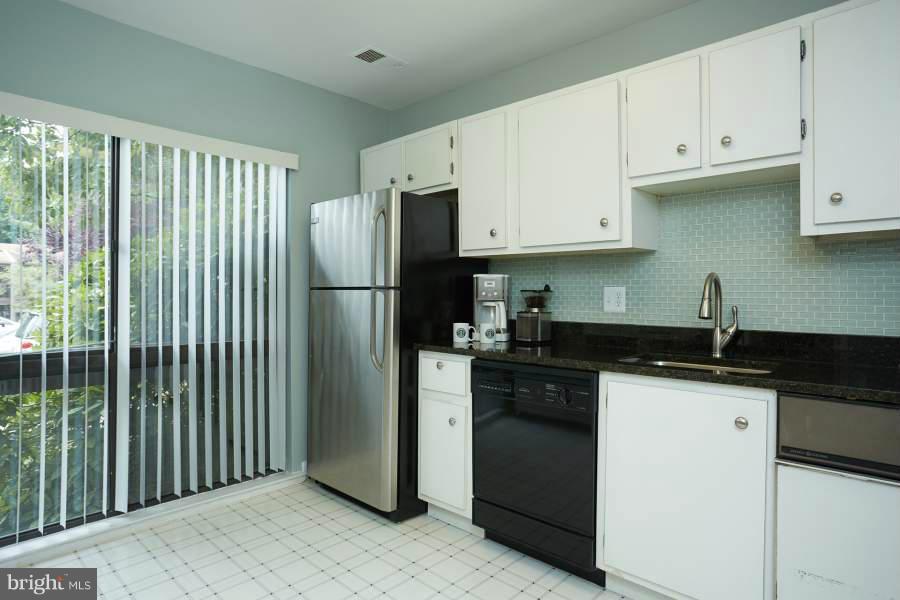 11602 Windbluff Court, Unit 8A1 Reston, VA 20191 - Photo 12 of 27 a kitchen with granite countertop a refrigerator a sink and white cabinets