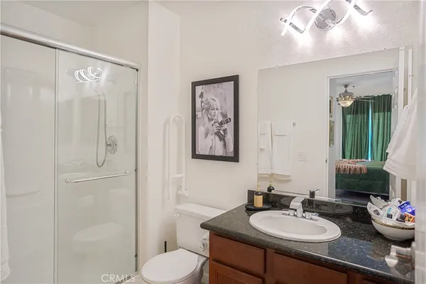 a bathroom with a granite countertop sink a toilet and a shower