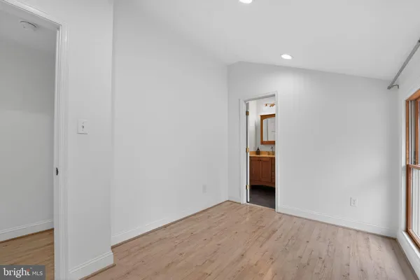 a view of an empty room with wooden floor and closet