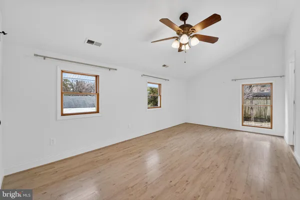 a view of an empty room with window and a ceiling fan