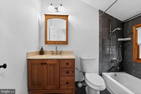 a bathroom with a toilet sink vanity tub and mirror