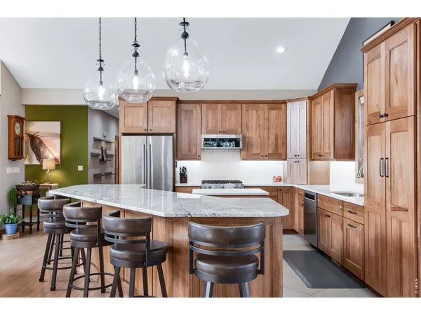 a open kitchen with stainless steel appliances granite countertop a stove kitchen island a dining table and chairs with wooden floor