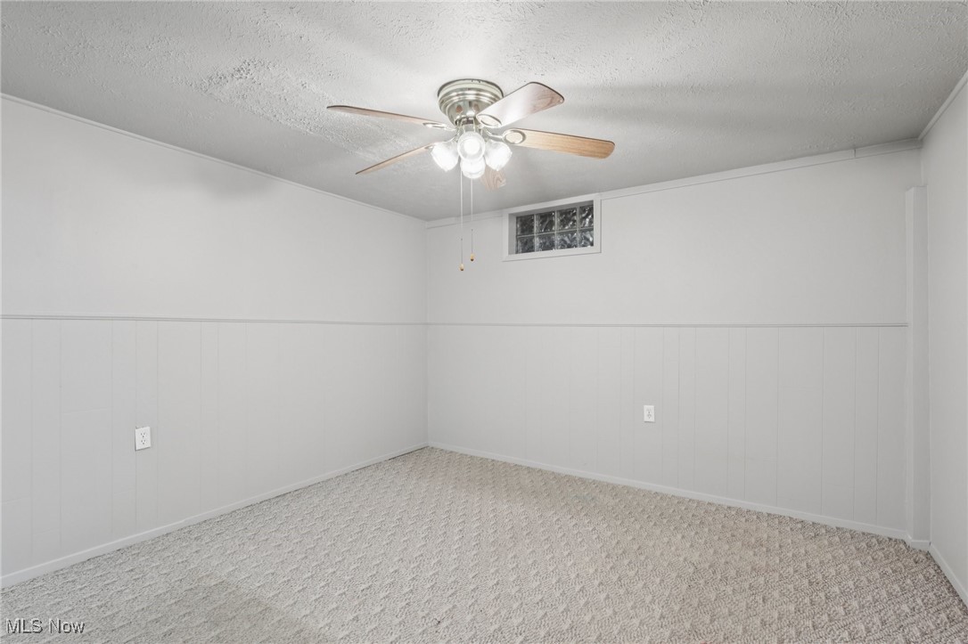 611 Wilson Street Struthers, OH 44471 - Photo 35 of 44 Spare room with a textured ceiling, a ceiling fan, wainscoting, and carpet floors