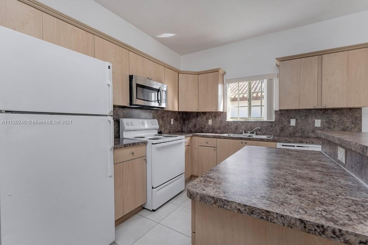 19064 Southwest 319th Street Homestead, FL 33030 - Photo 6 of 15 a kitchen with granite countertop white cabinets and white appliances