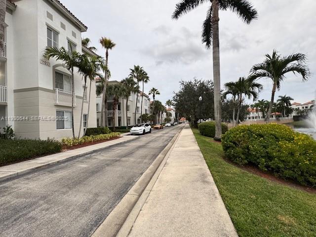 11033 Legacy Boulevard, Unit 302 Palm Beach Gardens, FL 33410 - Photo 27 of 28 a front view of multi story residential apartment building with a yard and palm trees