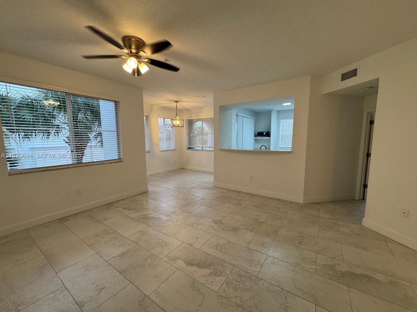11033 Legacy Boulevard, Unit 302 Palm Beach Gardens, FL 33410 - Photo 3 of 28 an empty room with chandelier fan and windows