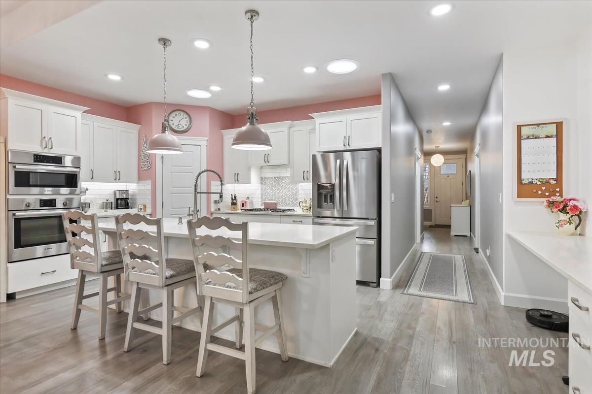 189 South Devon Avenue Star, ID 83669 - Photo 5 of 42 Kitchen with appliances with stainless steel finishes, a kitchen bar, white cabinets, an island with sink, and pendant lighting