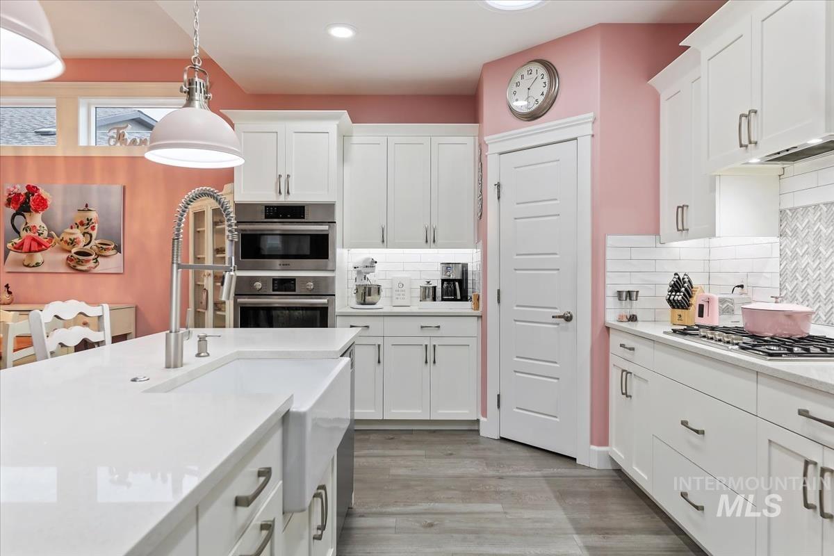 189 South Devon Avenue Star, ID 83669 - Photo 8 of 42 Kitchen featuring hanging light fixtures, white cabinets, light stone counters, light wood-style floors, and stainless steel appliances