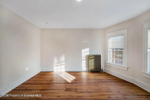 a view of empty room with wooden floor and window