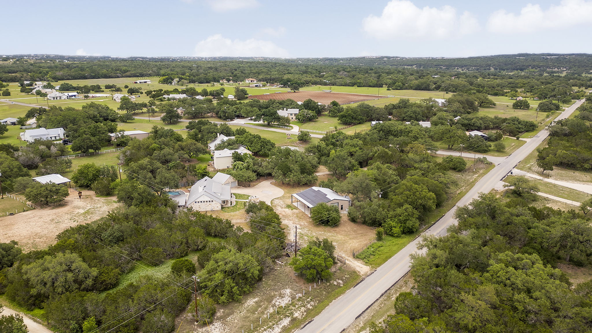 1129 Cedar Pass Road Driftwood, TX 78619 - Photo 38 of 40 These aerial shots really put everything into perspective. You can see how the main house, the matching detached garage, and the large workshop are positioned to create a private, functional compound.