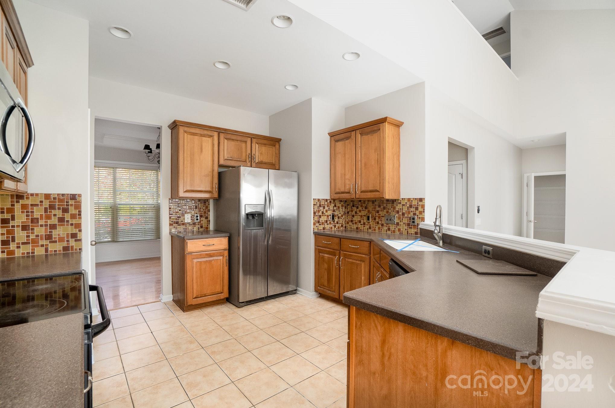2532 Coltsgate Road Waxhaw, NC 28173 - Photo 5 of 21 a kitchen with stainless steel appliances granite countertop a refrigerator a stove and white cabinets with wooden floor