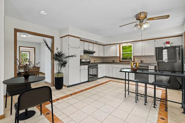 a kitchen with stainless steel appliances kitchen island granite countertop a stove top oven a sink a dining table and chairs