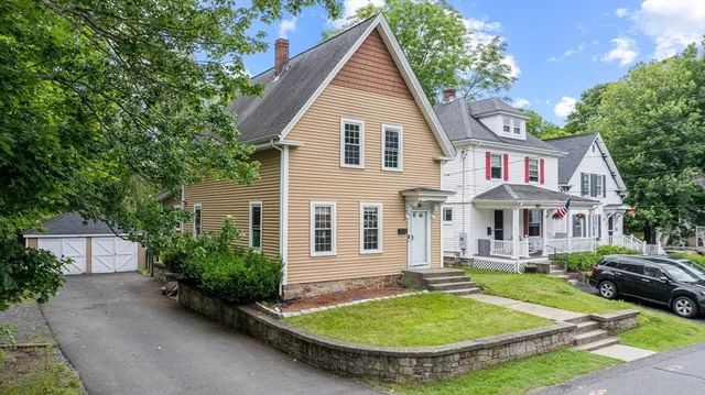 a view of a white house with a yard table and chairs