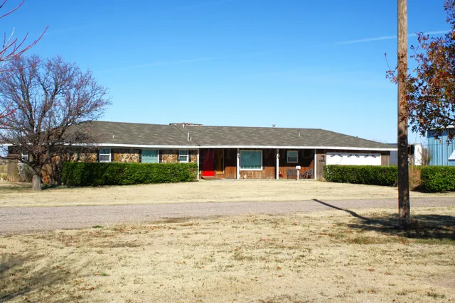 a front view of a house with a yard and a large tree