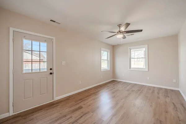 a view of an empty room with a window and wooden floor