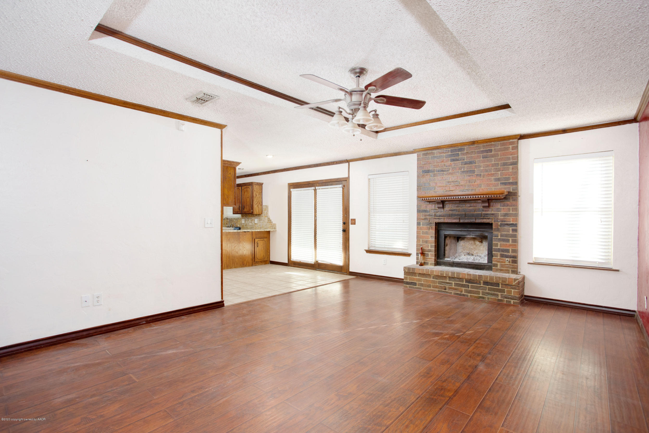 8213 Wrangler Trail Amarillo, TX 79110 - Photo 4 of 20 an empty room with wooden floor fireplace and windows