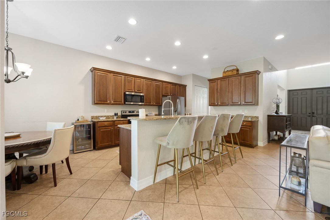 10117 Silver Maple Court Fort Myers, FL 33913 - Photo 11 of 49 a kitchen with stainless steel appliances kitchen island granite countertop a sink a stove a microwave a dining table and chairs