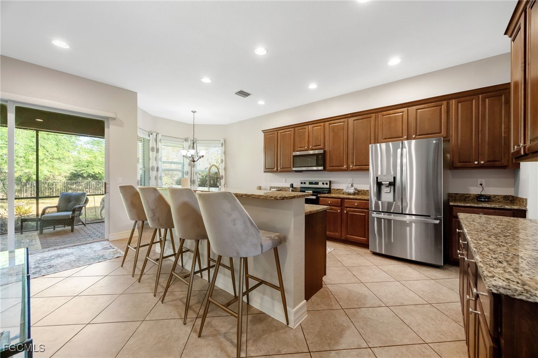 10117 Silver Maple Court Fort Myers, FL 33913 - Photo 7 of 49 a kitchen with stainless steel appliances granite countertop a stove a refrigerator a sink a dining table and chairs