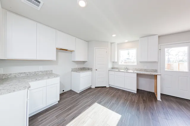 a kitchen with a white wooden cabinets and wooden floor