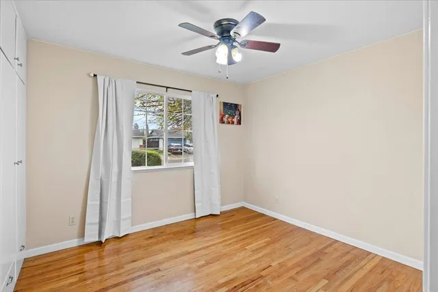 a view of a bedroom with wooden floor and window