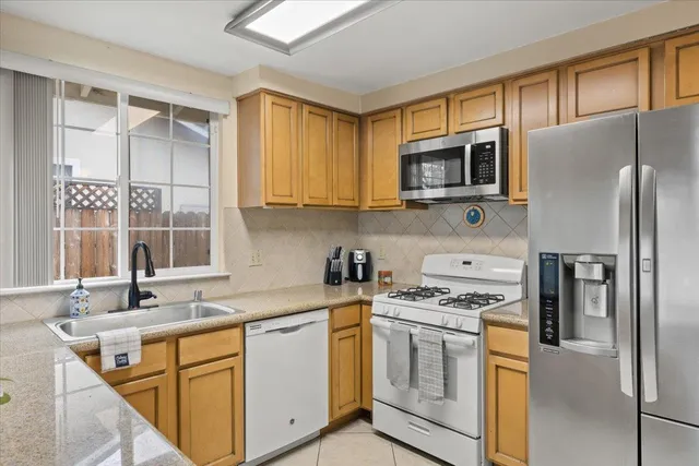 a kitchen with stainless steel appliances granite countertop a stove a sink and a refrigerator