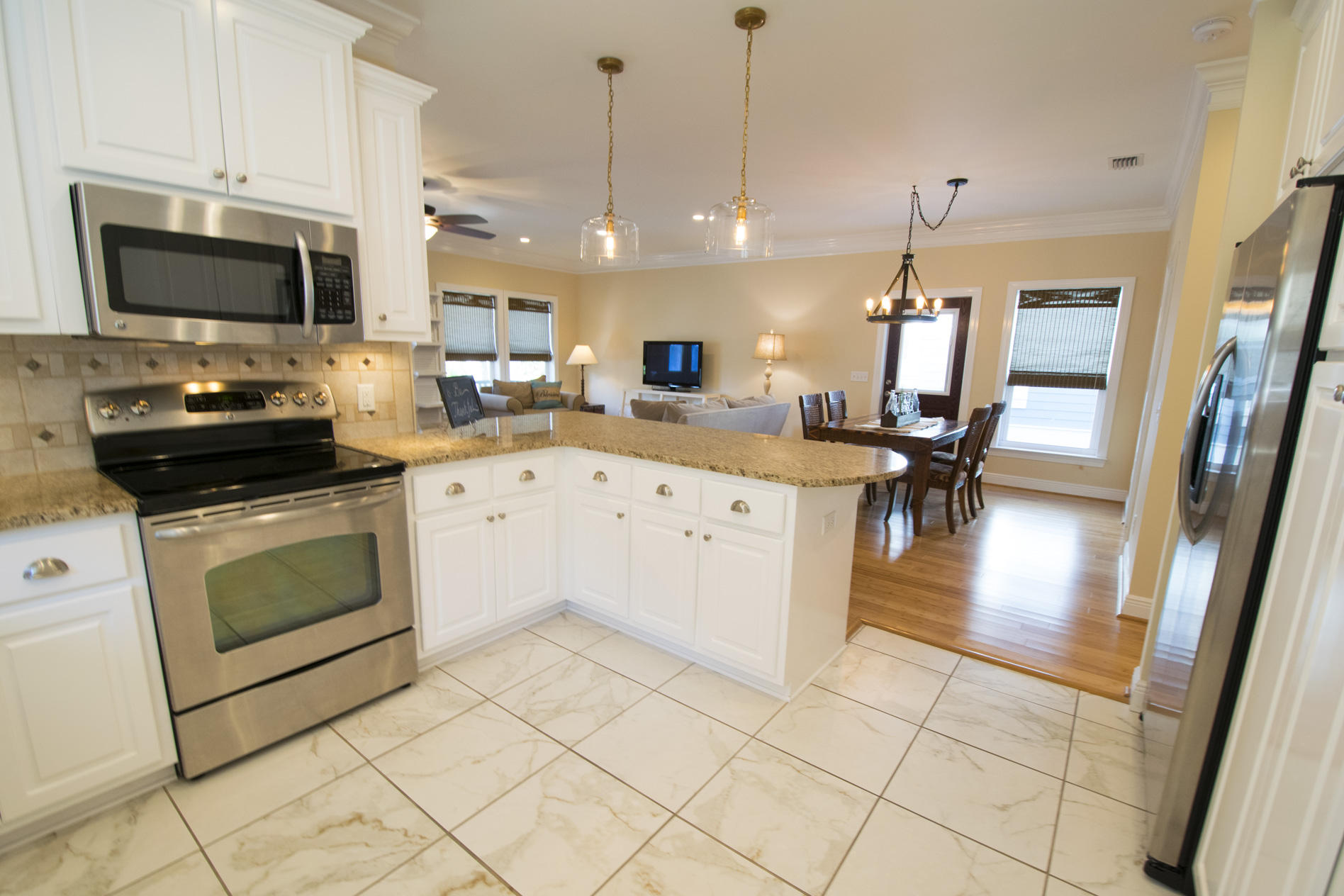 35 The Greenway Loop Inlet Beach, FL 32461 - Photo 14 of 37 a kitchen with stainless steel appliances kitchen island granite countertop a sink a stove a microwave a dining table and chairs with white cabinets
