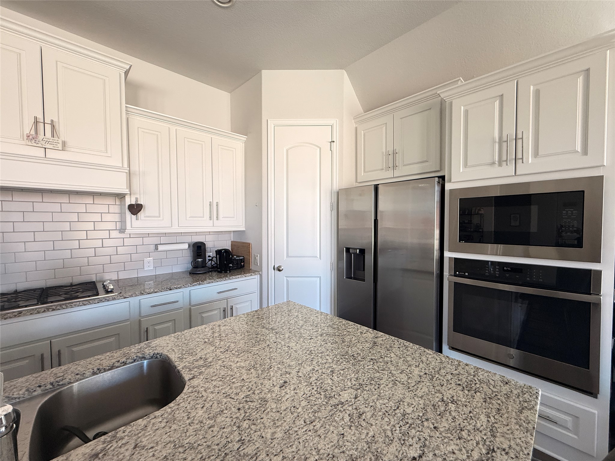 156 Santa Maria Street Georgetown, TX 78628 - Photo 11 of 40 Kitchen with stainless steel appliances, light stone counters, white cabinets, and decorative backsplash