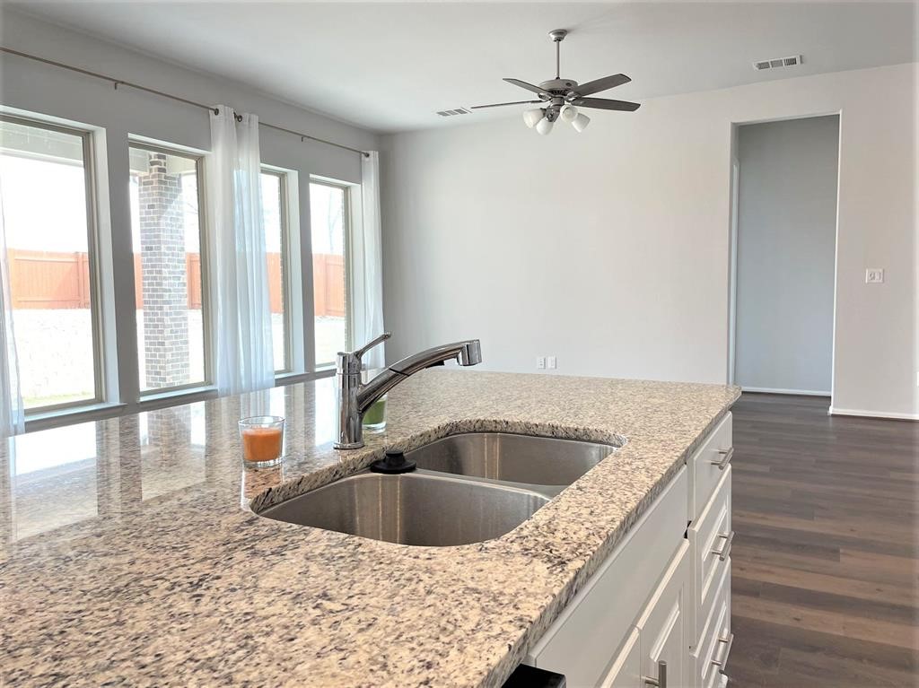 156 Santa Maria Street Georgetown, TX 78628 - Photo 14 of 40 Kitchen with dark wood finished floors, ceiling fan, light stone countertops, and white cabinetry