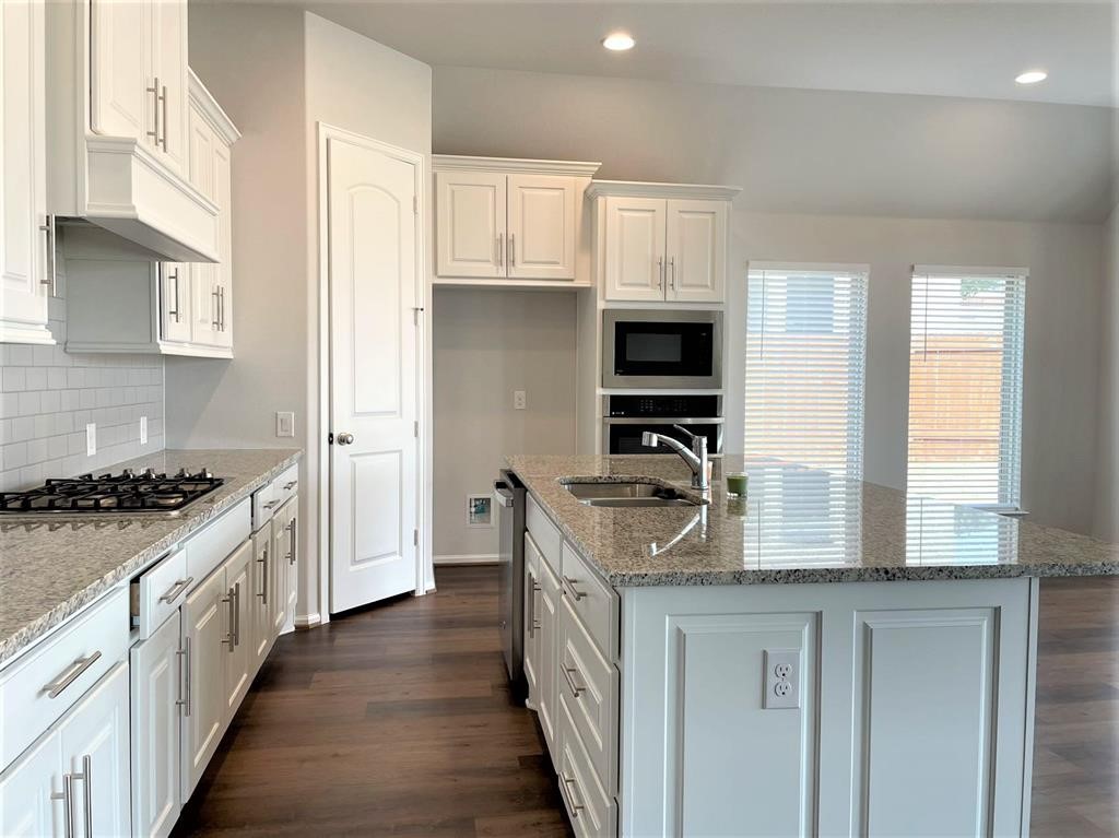 156 Santa Maria Street Georgetown, TX 78628 - Photo 15 of 40 Kitchen with white cabinets, a center island with sink, dark wood-style floors, light stone counters, and stainless steel appliances