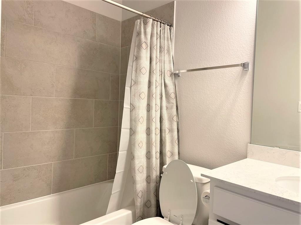 156 Santa Maria Street Georgetown, TX 78628 - Photo 33 of 40 Bathroom featuring a textured wall, vanity, and shower / bathtub combination with curtain