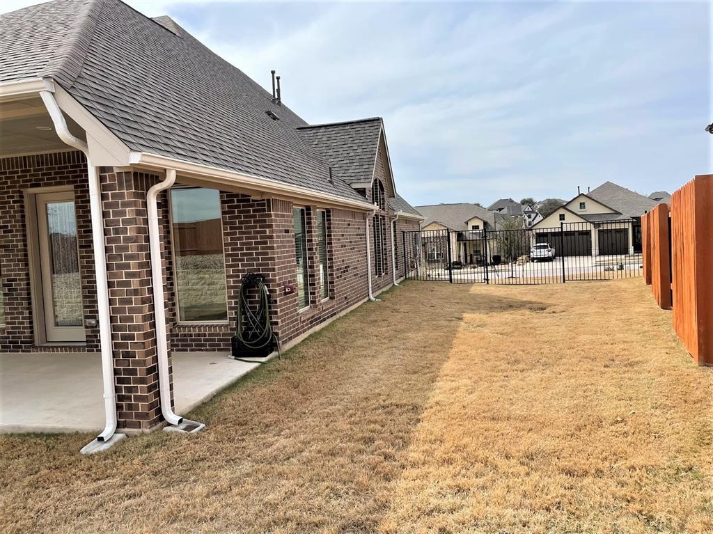 156 Santa Maria Street Georgetown, TX 78628 - Photo 36 of 40 View of side of property featuring brick siding, a shingled roof, a fenced backyard, and a patio area