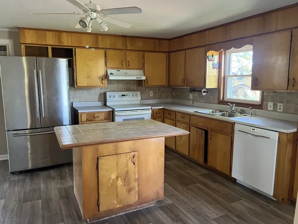 a kitchen with stainless steel appliances a sink a stove a refrigerator cabinets and wooden floor