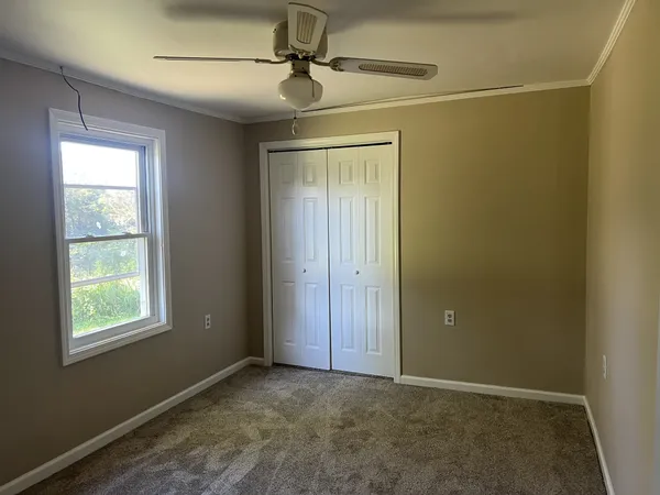 an empty room with windows and fan