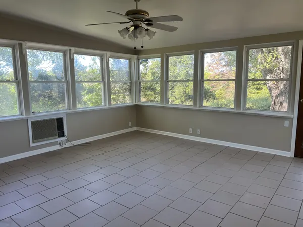 an empty room with windows and fan