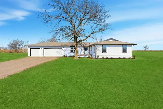 a front view of a house with a yard and trees